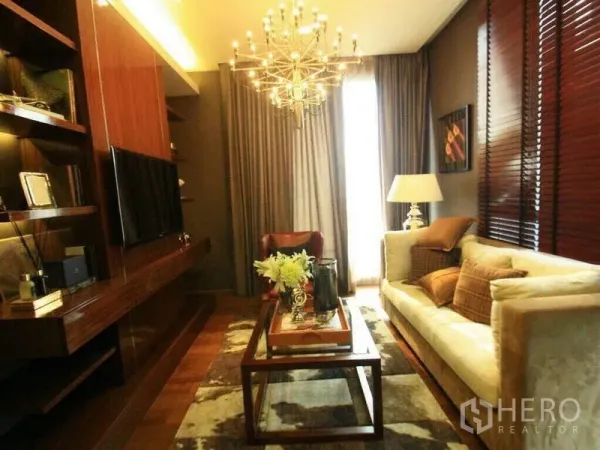 คอนโด ให้เช่าหรือขายในWatthana, Bangkok - ห้องนั่งเล่นโทนอุ่นพร้อมโคมระย้า โซฟาครีม ชั้นไม้ ทีวี และผ้าม่านสูงในคอนโดทองหล่อ