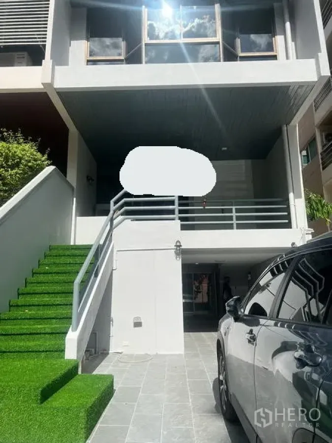 Townhouse for rent in Watthana, Bangkok - Contemporary townhouse facade with covered carport and artificial grass steps.