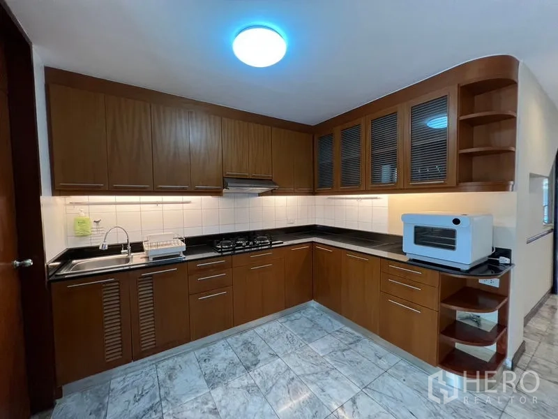 ทาวน์เฮาส์ ให้เช่าหรือขายในSuan Luang, Bangkok - ครัวรูปตัวแอล ตู้ไม้ เคาน์เตอร์หินสีดำ และเตาแก๊ส