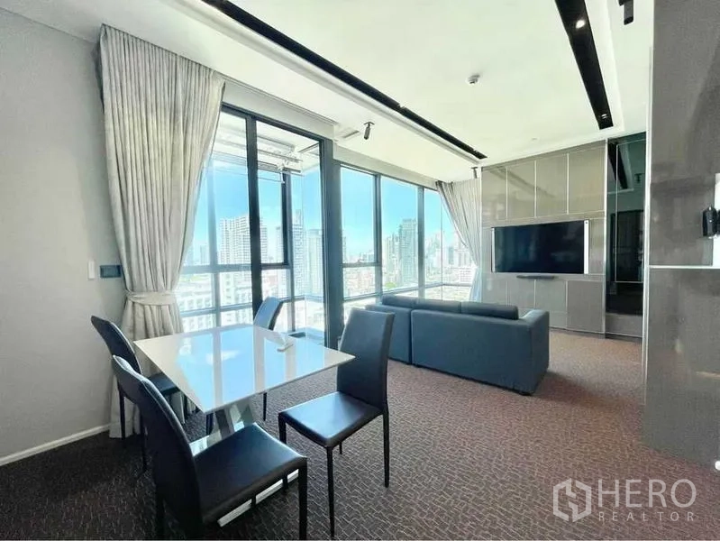 Condominium for rent in Watthana, Bangkok - Open living and dining area with sofa set, dining table and balcony access to panoramic skyline views.