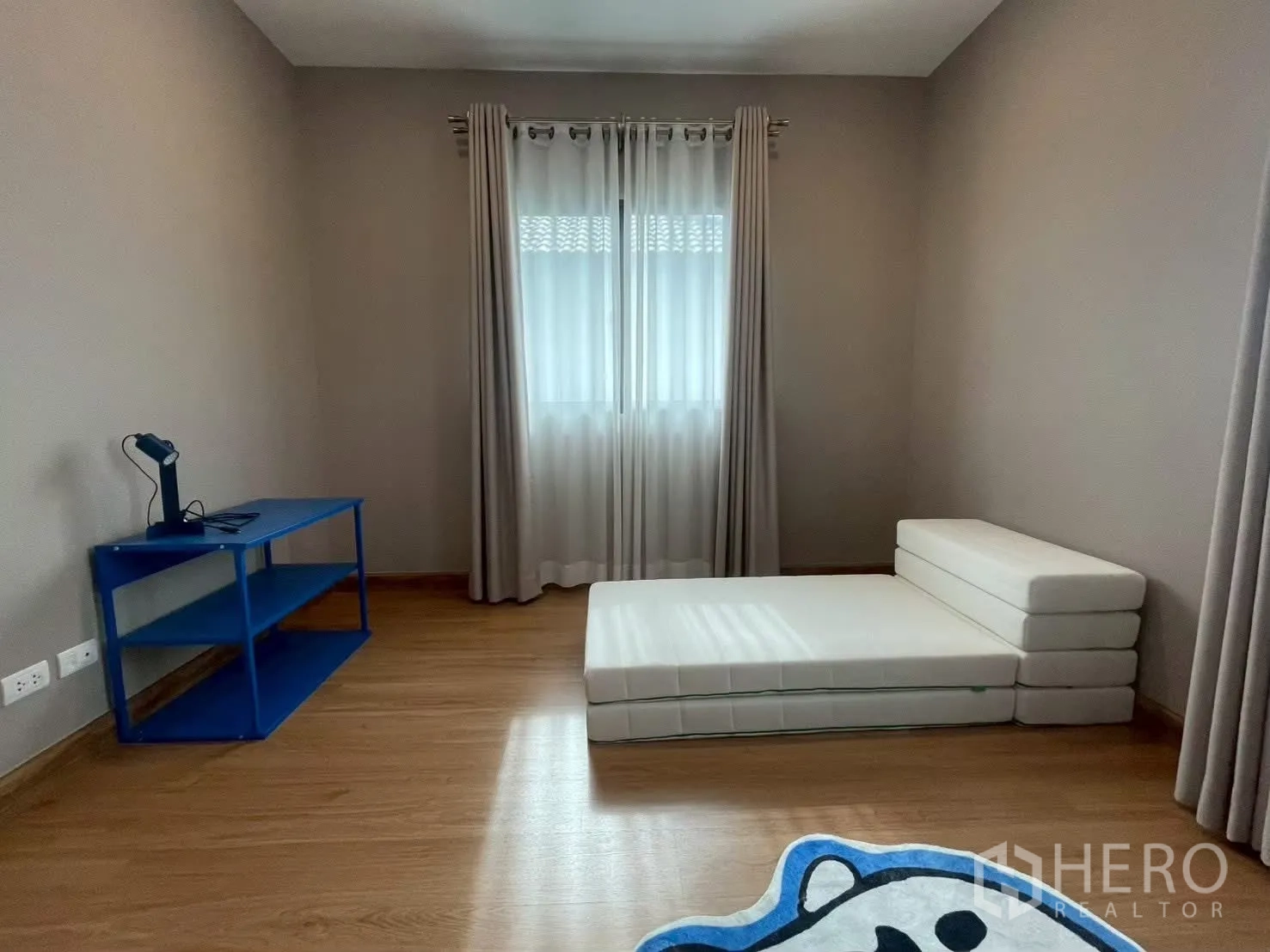 Detached House for rent in Bang Phli, Samut Prakan - Minimal bedroom with foldable floor mattress, blue desk and a curtained window.