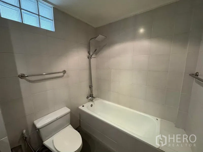 Condominium for rent in Yan Nawa, Bangkok - Bathroom with bathtub, handheld shower and light gray tiled walls.