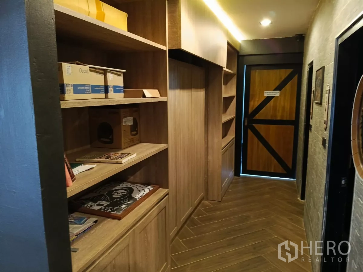 Retail Space for rent - Narrow hallway with wood cabinetry and shelving under soft lighting.
