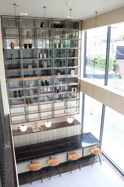 零售空间 出租在Phra Khanong, Bangkok - 俯视现代零售吧台，高展示架、吊灯与吧椅，临近整面玻璃墙。