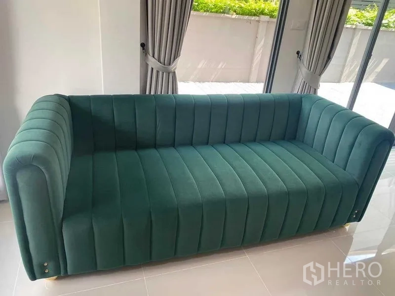 独立式住宅 出租在Khan Na Yao, Bangkok - 客厅一角，绿色绒面沙发靠近落地推拉门。