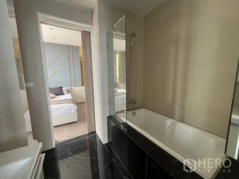 คอนโด ขาย - ห้องน้ำโมเดิร์นมีอ่างอาบน้ำ กั้นกระจก และพื้นหินอ่อนสีดำ
