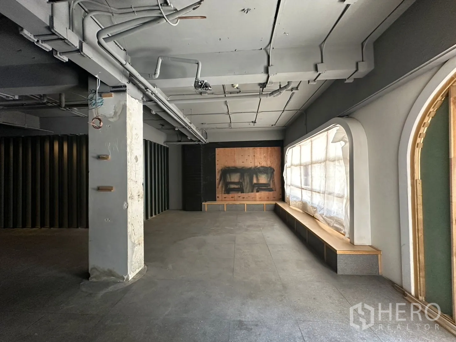 Retail Space for rent in Watthana, Bangkok - Open-plan retail interior with exposed ceiling pipes, columns, and arched window bench seating.