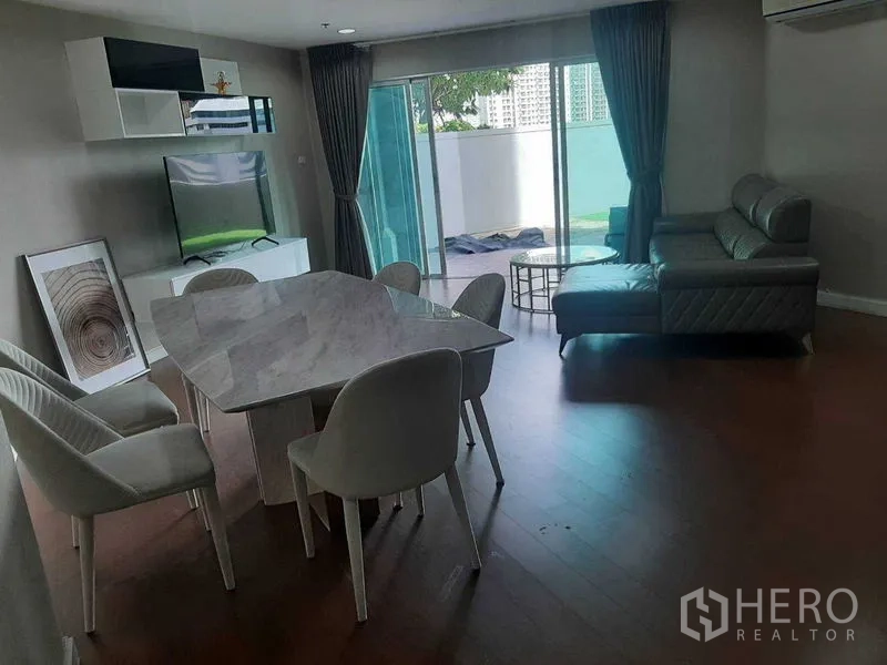 Condominium for rent or sale in Huai Khwang, Bangkok - Open-plan living and dining room with sofa, TV unit and balcony terrace