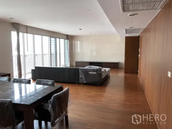 อพาร์ทเมนท์ ให้เช่าในWatthana, Bangkok - ห้องนั่งเล่นและรับประทานอาหารแบบเปิดโล่ง พื้นไม้ หน้าต่างสูงจรดเพดาน และมุมมองสู่ระเบียง ในอพาร์ตเมนต์สมัยใหม่