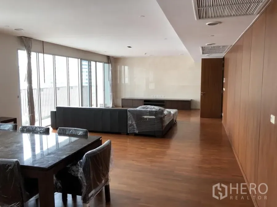 อพาร์ทเมนท์ ให้เช่าในWatthana, Bangkok - ห้องนั่งเล่นและรับประทานอาหารแบบเปิดโล่ง พื้นไม้ หน้าต่างสูงจรดเพดาน และมุมมองสู่ระเบียง ในอพาร์ตเมนต์สมัยใหม่