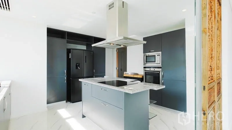 คอนโด ขาย - ครัวสไตล์โมเดิร์นมีไอส์แลนด์ เตาไฟฟ้า เคาน์เตอร์หิน ตู้สีเข้ม และเตาอบบิลท์อิน