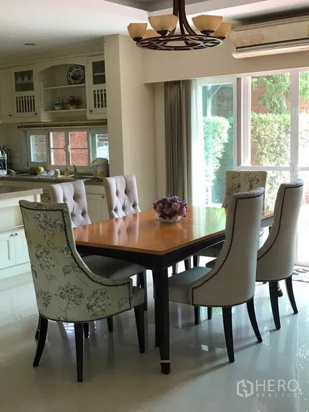 Detached House for sale in Pak Kret, Nonthaburi - Dining area for six with upholstered chairs beside the kitchen and glass doors.