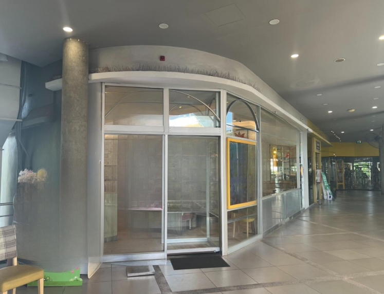 零售空间 出租在Khlong Toei, Bangkok - 商场转角零售铺面，落地玻璃门面与推拉门，明亮的瓷砖走廊。