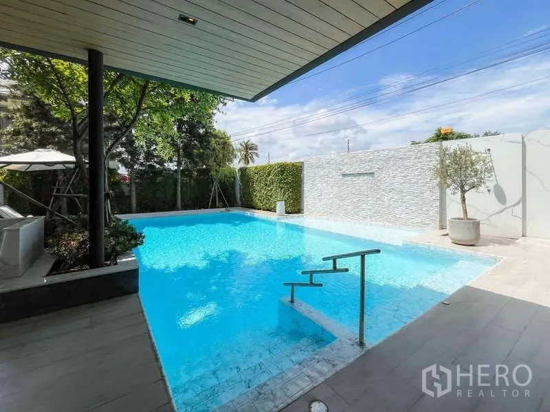 Detached House for sale in Bang Lamung, Chon Buri - Private pool with entry steps and white feature wall under a partially covered terrace.