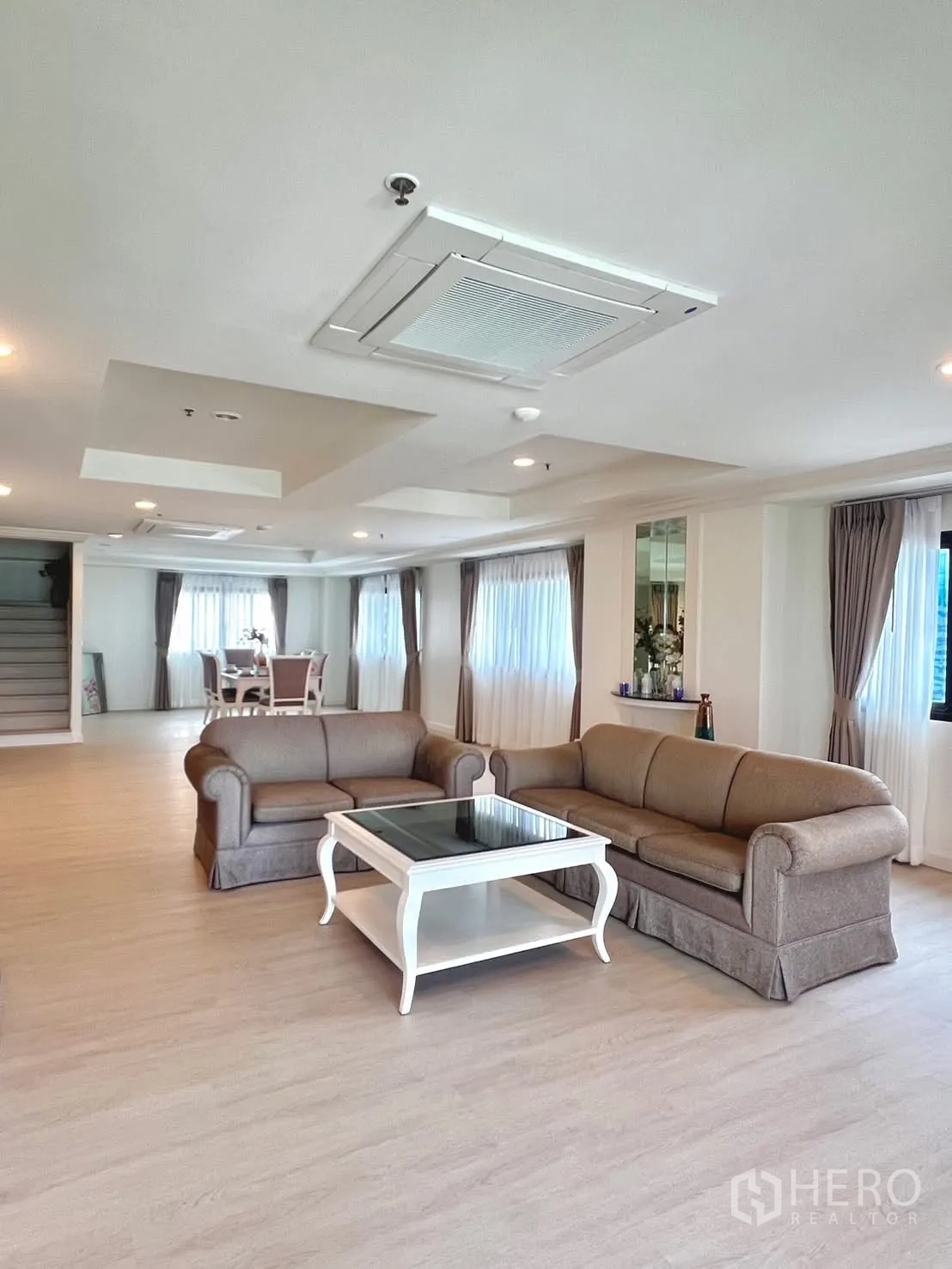 Condominium for rent in Khlong Toei, Bangkok - Open-plan living and dining area with staircase and large windows.