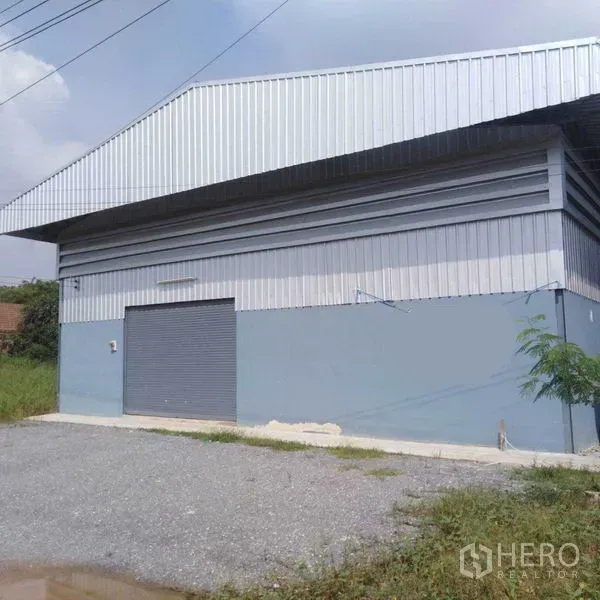 คลังสินค้า ให้เช่าในBang Yai, Nonthaburi - ภายนอกด้านข้างของโกดังผนังเมทัลชีท พร้อมประตูม้วนและลานจอดหินคลุก