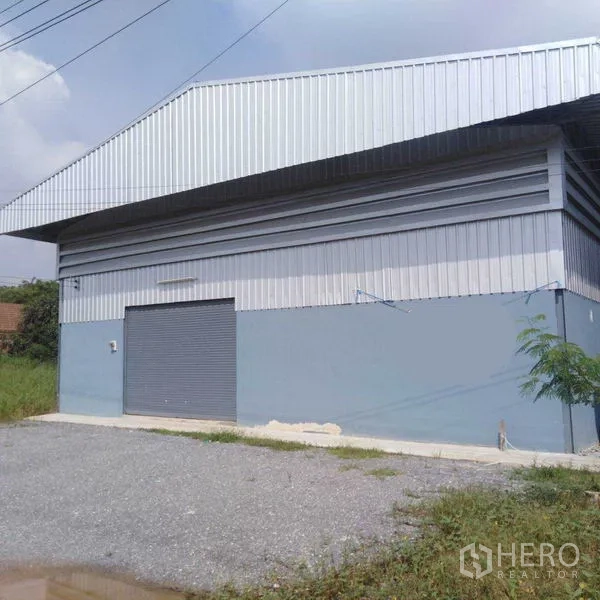 คลังสินค้า ให้เช่าในBang Yai, Nonthaburi - ภายนอกด้านข้างของโกดังผนังเมทัลชีท พร้อมประตูม้วนและลานจอดหินคลุก