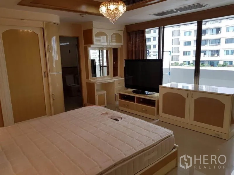 คอนโด ให้เช่าหรือขายในWatthana, Bangkok - ห้องนอนมีโคมระย้า ตู้วางทีวี และประตูกระจกสไลด์ออกสู่ระเบียงกว้าง