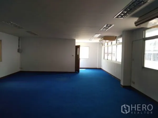 Warehouse for rent in Bang Phli, Samut Prakan - Air-conditioned office room with blue carpet, large windows and fluorescent ceiling lights.