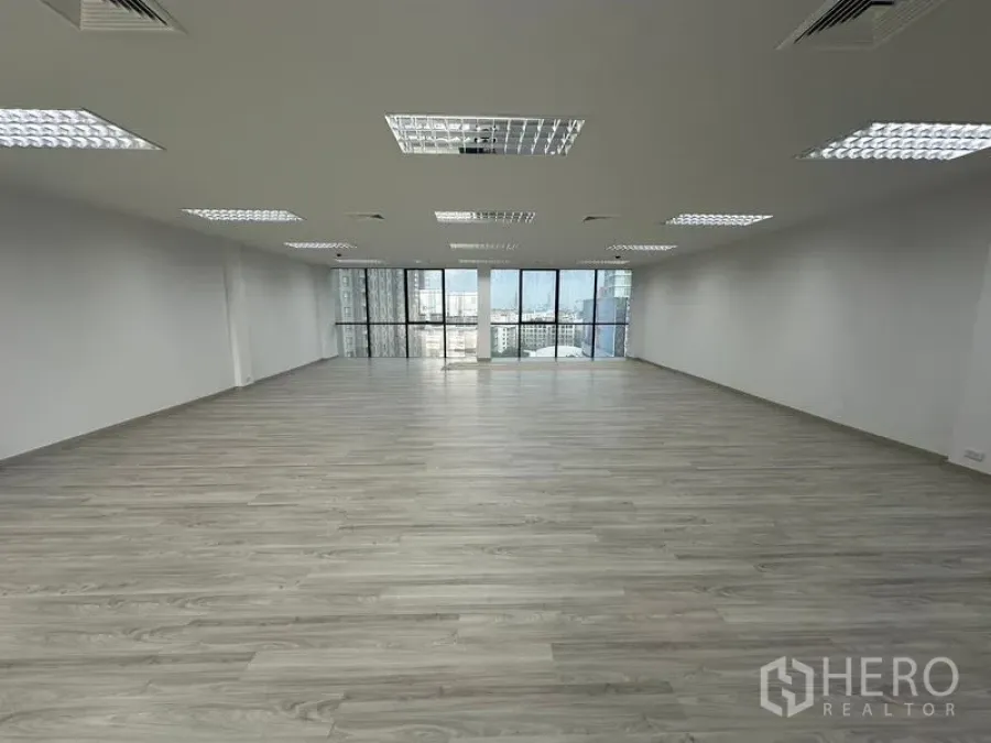Office Space for rent - Wide open workspace with uniform ceiling lights and full-height windows facing the city