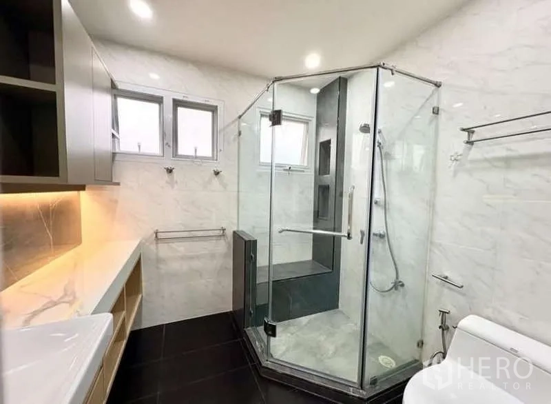 Detached House for rent in Phasi Charoen, Bangkok - Contemporary bathroom with glass shower enclosure and marble-effect walls.