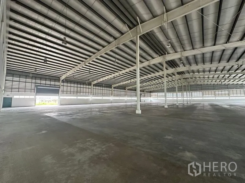 工厂 出租在Pathum Thani - 厂房内部带卷帘门与大跨度立柱。