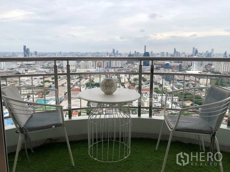 公寓 出售在Yan Nawa, Bangkok - 弧形阳台，两把椅子与圆桌，俯瞰曼谷天际线。