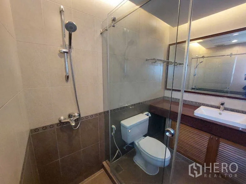 房间 出租 - 现代浴室，玻璃淋浴间、马桶、宽镜面与中性色墙砖。