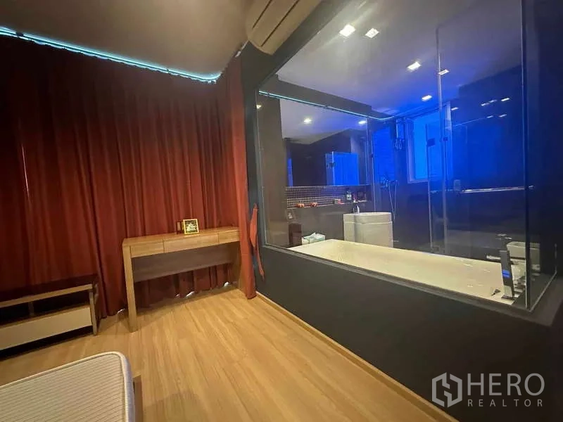 คอนโด ขายในPhaya Thai, Bangkok - ห้องนอนพร้อมผนังกระจกมองเห็นห้องน้ำที่มีอ่างอาบน้ำ พร้อมผ้าม่านทึบสีแดง