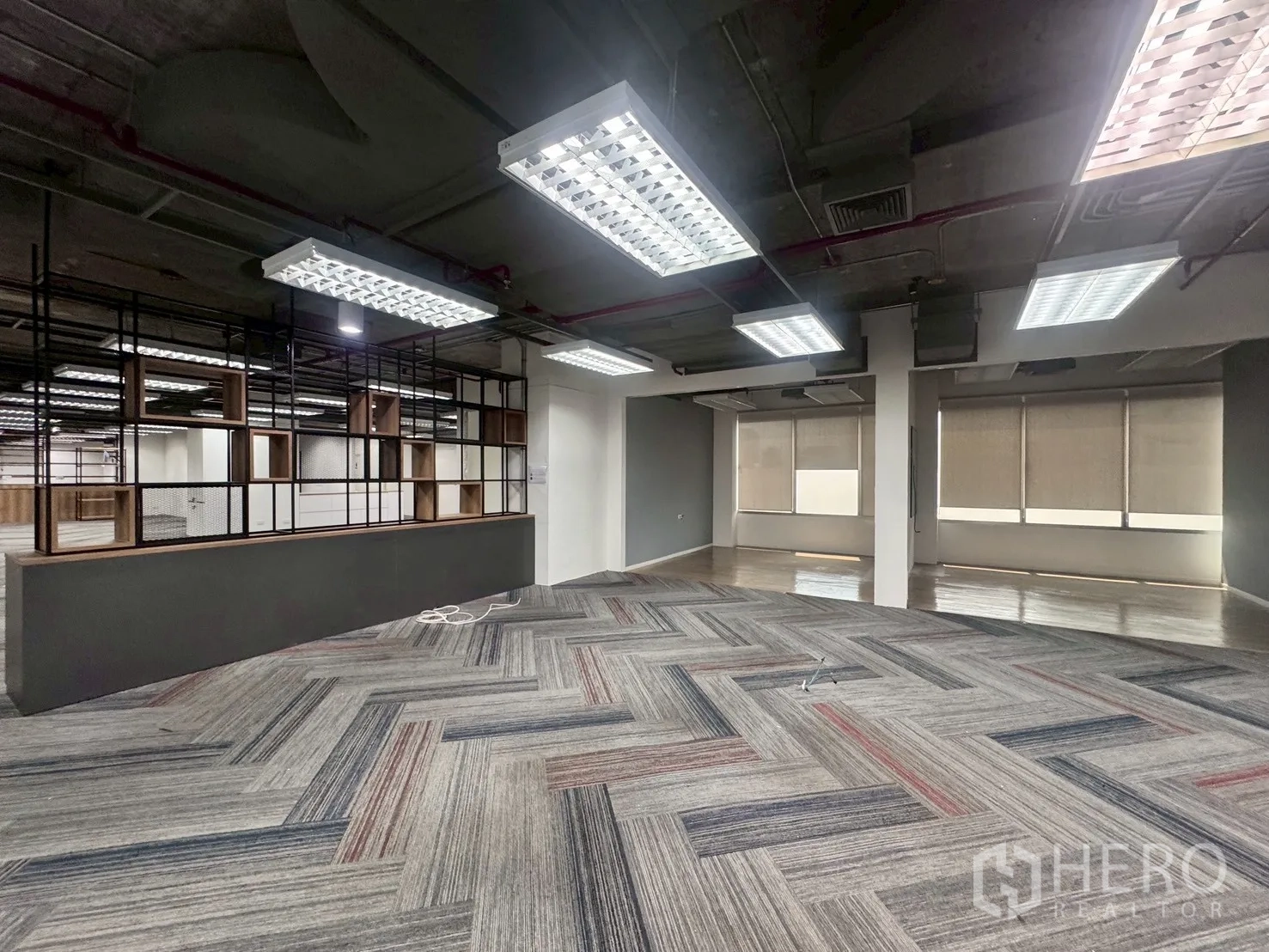 办公室 for rent in Watthana, Bangkok - 协作区设黑色网格隔断，旁为铺木地板并配卷帘的区域。