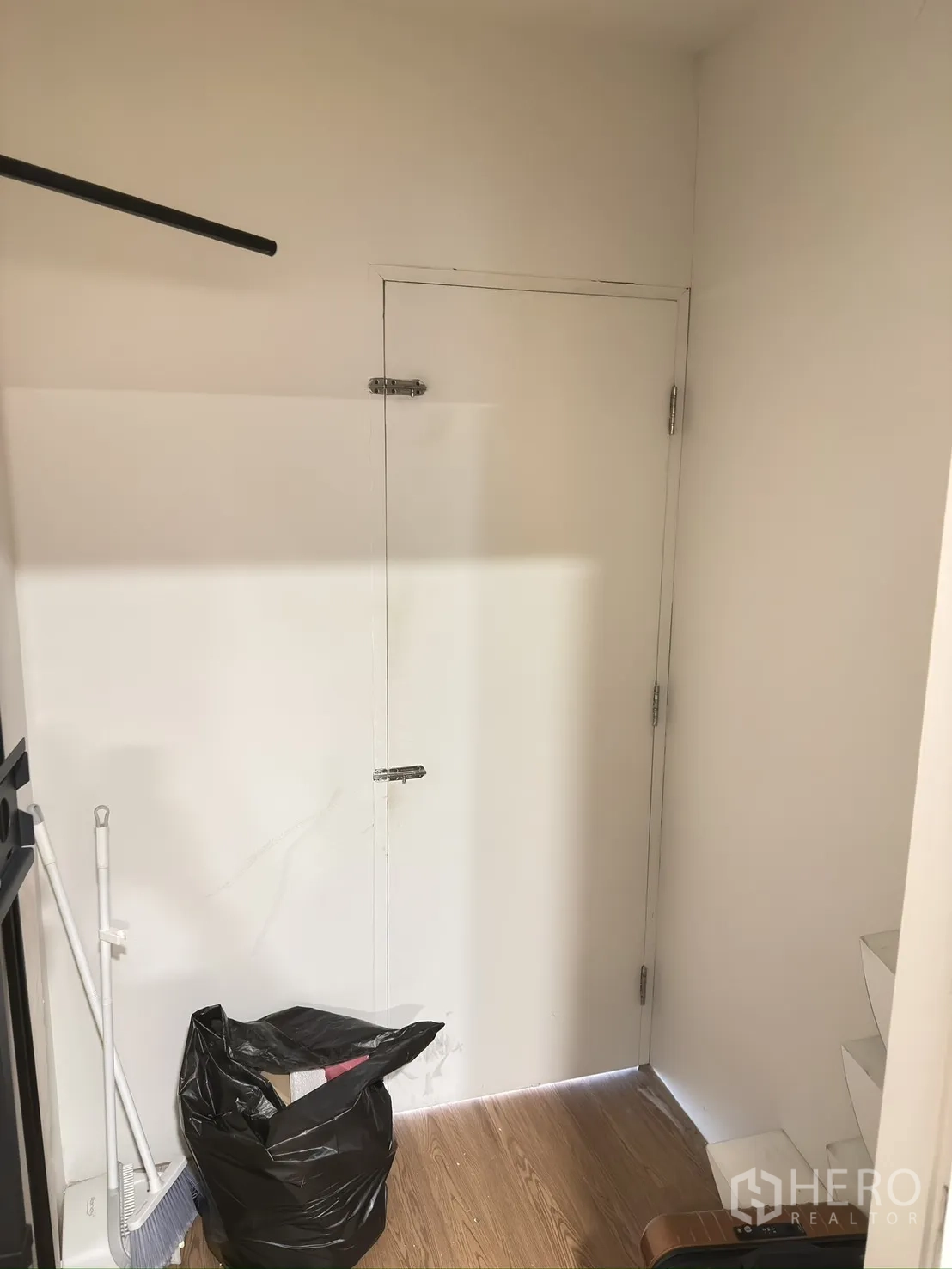 Retail Space for rent in Khlong Toei, Bangkok - Small storage corner with a white door, cleaning tools, and wood-style flooring.