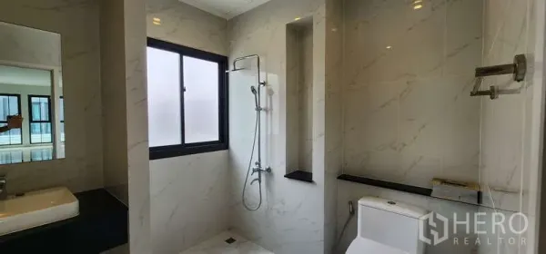 Home Office for rent - Modern bathroom with window, walk-in shower, and toilet finished in marble-look tiles.