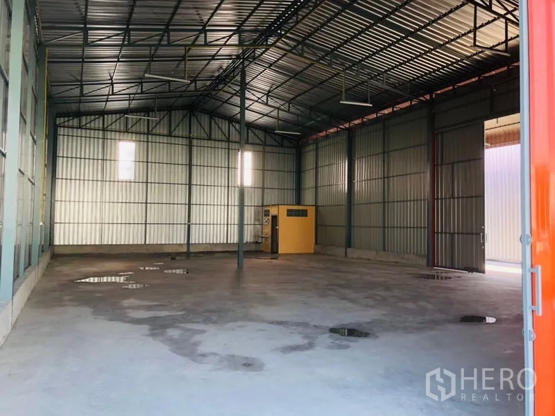 Warehouse for rent in Wang Thonglang, Bangkok - Open warehouse interior with high steel roof, concrete floor and roller-door access.