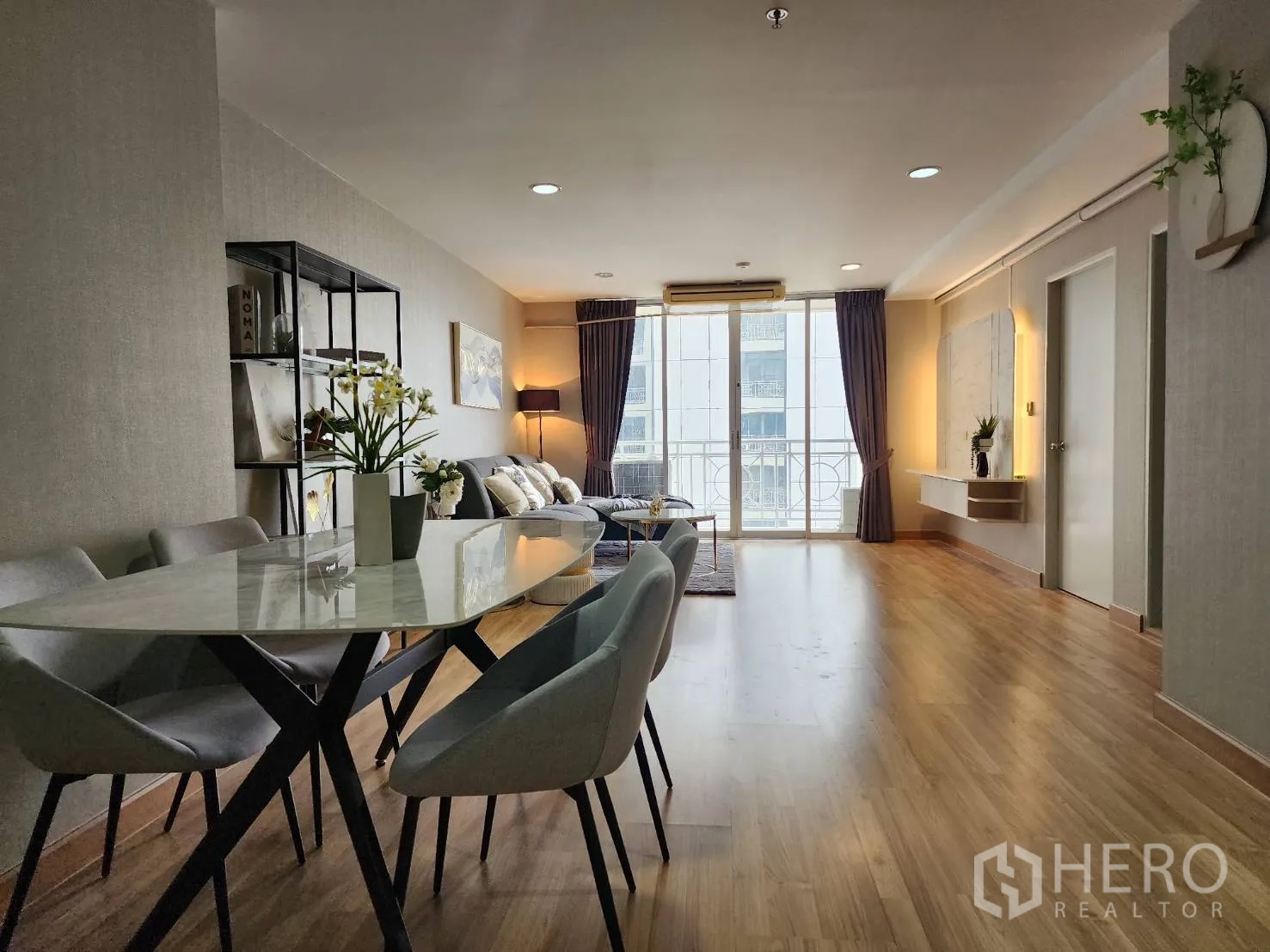 Condominium for rent in Watthana, Bangkok - Dining zone with oval marble table and four chairs beside the living area.