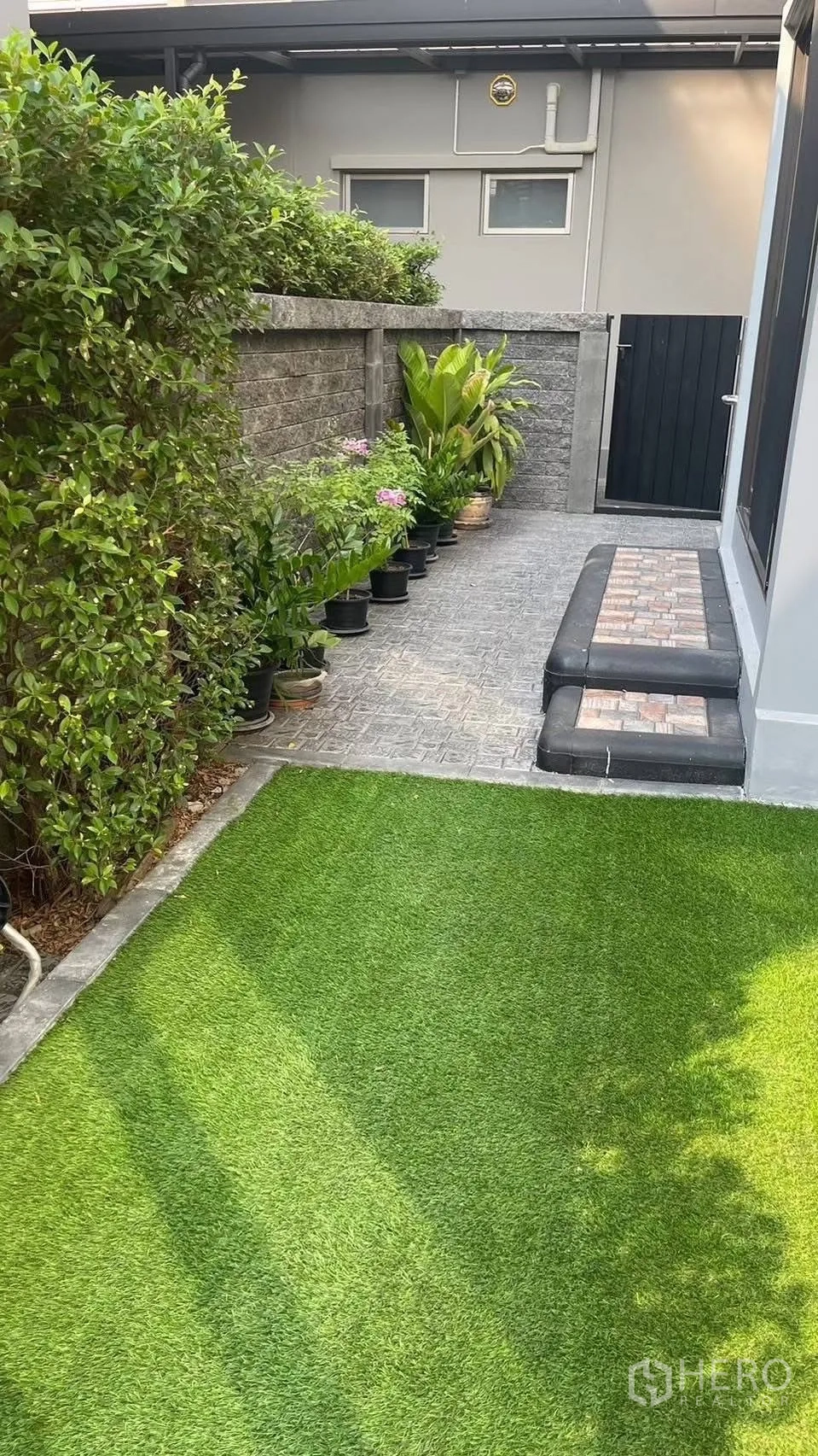 Detached House for rent in Prawet, Bangkok - Back garden corner with artificial grass, potted plants and gate.