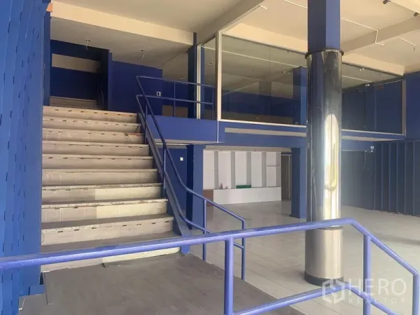 店屋 出租在Watthana, Bangkok - 店屋一层开放式空间，宽楼梯、夹层玻璃房与不锈钢立柱。