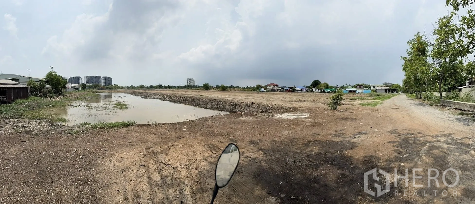 Land for sale in Bang Phli, Samut Prakan - Panoramic view showing the waterway, open ground, and a small access road lined with trees.