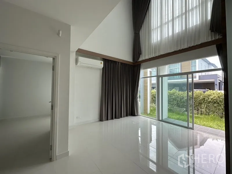 บ้าน ขายในLam Luk Ka, Pathum Thani - ห้องนั่งเล่นเพดานสูงสองชั้น ผนังกระจกเต็มบานและผ้าม่าน