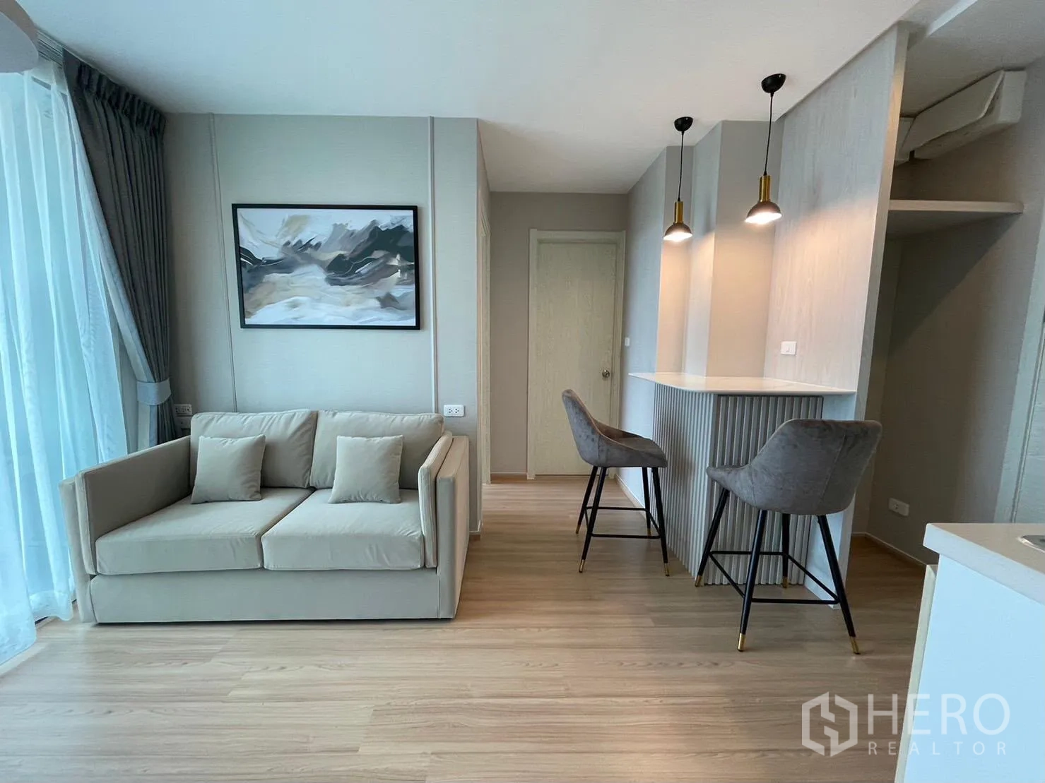 คอนโด for rent in Suan Luang, Bangkok - ห้องนั่งเล่นสว่างพร้อมโซฟาสีครีม หน้าต่างบานใหญ่ และเคาน์เตอร์บาร์พร้อมโคมไฟห้อย