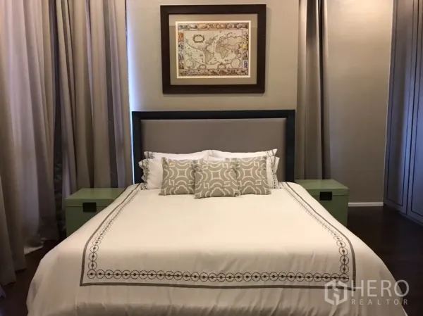 Condominium for rent or sale in Huai Khwang, Bangkok - Primary bedroom with upholstered headboard, neutral bedding, framed art and full-height curtains.