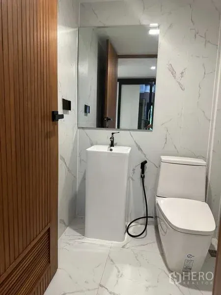 Detached House for rent in Suan Luang, Bangkok - Modern powder room with pedestal sink, toilet and marble-effect walls.