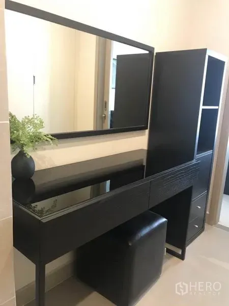 Condominium for rent or sale in Pathum Wan, Bangkok - Modern black dressing table with large mirror and ottoman in a bright condo bedroom.