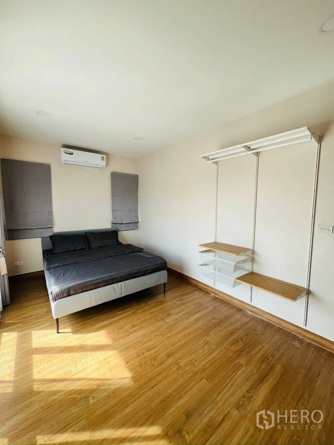 บ้านเดี่ยว for rent in Prawet, Bangkok - ห้องนอนกว้างพร้อมแอร์ เตียง และชั้นวางติดผนังบนพื้นไม้ลามิเนต.