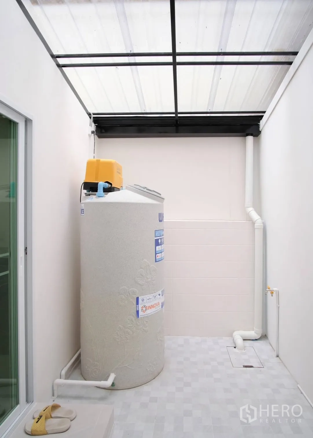 Townhouse for rent in Bang Phli, Samut Prakan - Covered utility area with water tank and pump beside a sliding door.