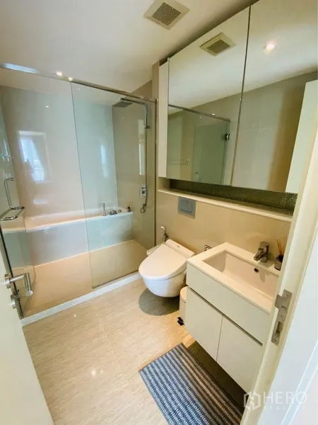 คอนโด ให้เช่าในWatthana, Bangkok - ห้องน้ำหลักพร้อมฉากกั้นกระจก อ่างล้างหน้า ตู้เก็บของ และโถสุขภัณฑ์โทนอ่อน