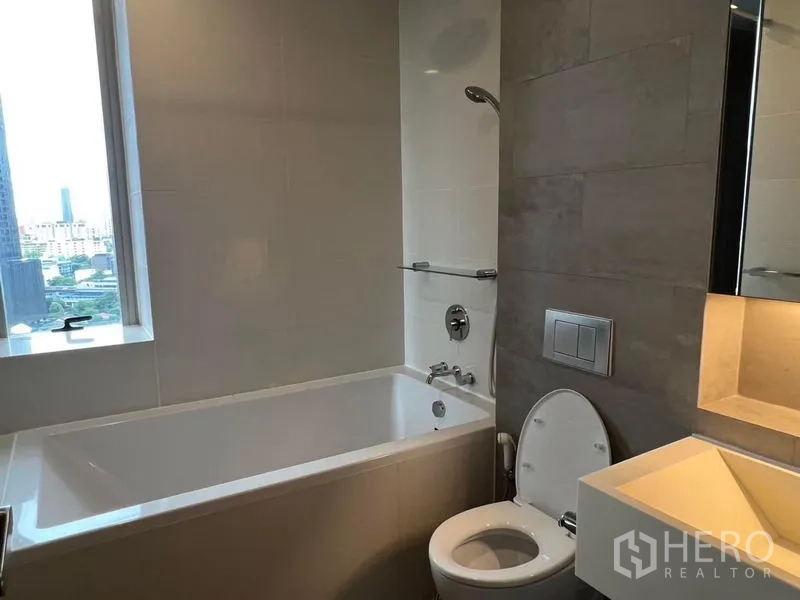 คอนโด ให้เช่า - ห้องน้ำโมเดิร์น มีอ่างอาบน้ำ โถสุขภัณฑ์ อ่างล้างหน้า และหน้าต่างเห็นวิวเมือง