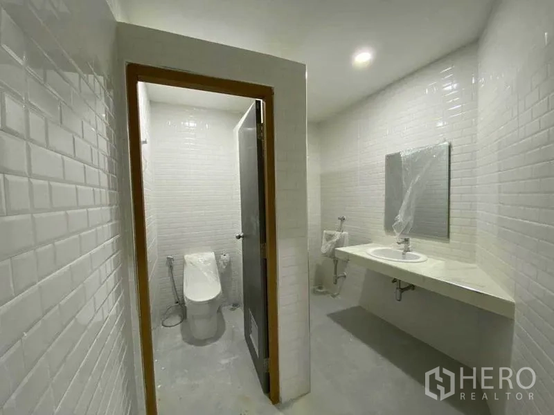 零售空间 出售在Khlong Toei, Bangkok - 白色地铁砖墙的卫生间，带坐便器、洗手台与镜子