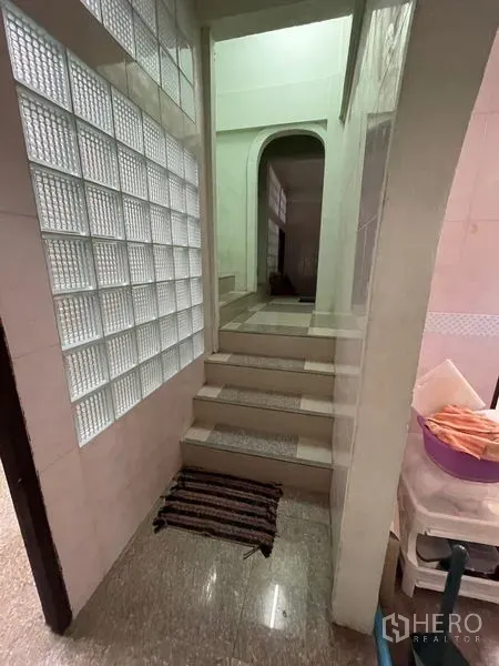 Shophouse for sale in Sathon, Bangkok - Short stairway with glass-block wall and arched doorway leading to rear rooms.