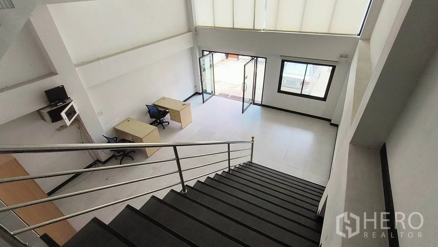 Office Space for rent in Khlong Toei, Bangkok - Staircase view down to the lobby with desks near the glass entrance.