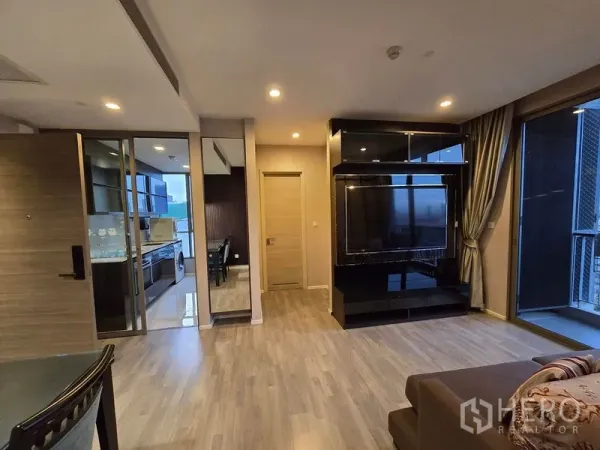 Condominium for rent - Living area with built-in TV wall, sliding door to enclosed kitchen and access to the balcony.